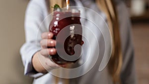 Female hand holding fresh beet smoothie in jar