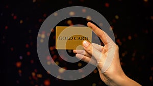 Female hand holding gold card on sparkling background, wealthy life, VIP club