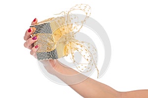 Female hand holding gold and yellow gift box with a bow