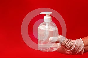 Female HAND holding Hand sanitizer in gel bottle on red background.