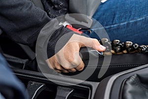 Female hand holding handbrake lever inside car