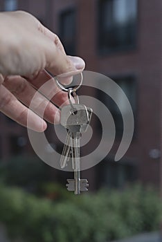 Female Hand Holding House Keys .agent handing over house keys in hand. Close-up view of keys from new home