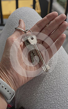 Female Hand Holding House Keys .agent handing over house keys in hand. Close-up view of keys from new home