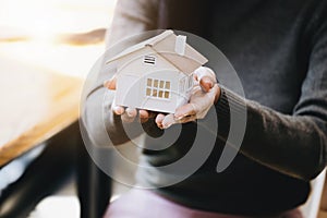 Female hand holding a house model, insurance concept and home loan.