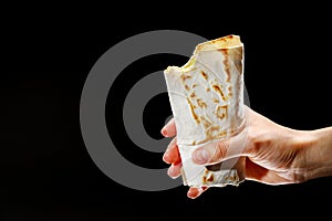 Female hand holding a kebab on a black background, fajitas, pita bread, shawarma
