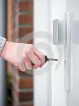 Female hand holding key to insert in door lock