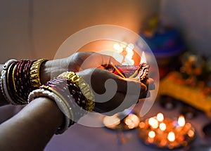 Female hand holding lit earthen diwali lamp