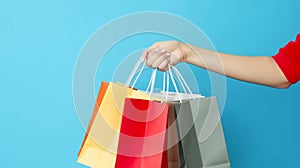 Female hand holding many colorful shopping bags on blue background