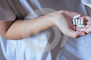 Female hand holding a medicine,Woman hands with pills on spilling pills out of bottle photo