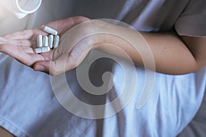 Female hand holding a medicine,Woman hands with pills on spilling pills out of bottle photo