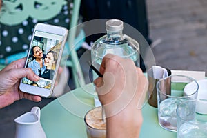 Female hand holding a mobile phone while having coffee looking photos.