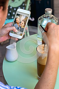 Female hand holding a mobile phone while having coffee looking photos.