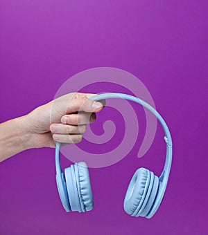 Female hand holding modern wireless blue headphones