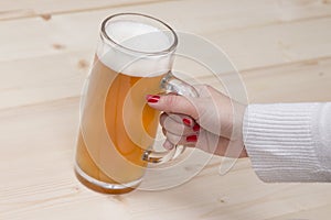 Female hand holding a mug of draft beer.