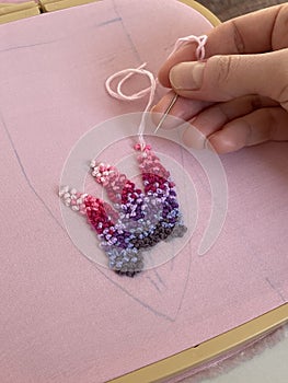 Female hand holding needle working on flower pattern