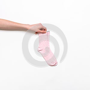 Female hand holding pair of pink modern trendy women`s cotton socks on white background. Fashionable socks store. Socks shopping,