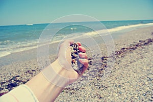 Female hand holding pebbles on the beach, retro/vintage