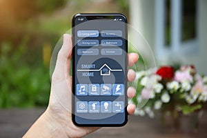 Female hand holding phone with app smart home on screen