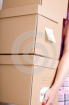 Female hand holding pile of brown cardboard boxes