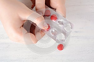 Female hand holding a pill.