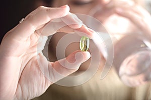 Female hand holding a pill.