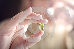 Female hand holding a pill.