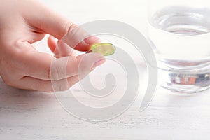 Female hand holding a pill.