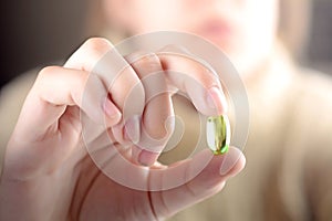 Female hand holding a pill.