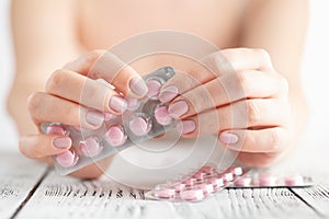 Female Hand holding a pink pill.