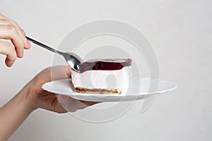 Female hand holding plate and spoot with sweet cheese dessert with cherry