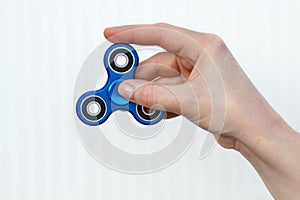 Female hand holding popular fidget spinner toy on white background, anxiety relief toy, anti stress and relaxation fidgets