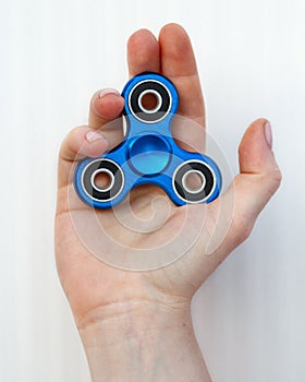 Female hand holding popular fidget spinner toy on white background, anxiety relief toy, anti stress and relaxation fidgets