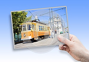 A female hand holding an postcard about the historical trasportation of Porto - on background the `Igreja do Carmo e Carmelitas`