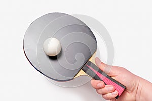 Female hand holding a racket with ping pong ball on a white background, top view.