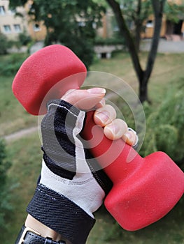 Female hand holding a red dumbbell.