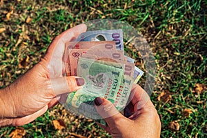 Female hand holding Romanian lei - code RON - money banknotes in denominations of 100, 10 & 1 leu