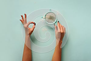 Female hand holding sieve flour on blue background. Baking and cooking concept. Banner with copy space