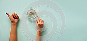 Female hand holding sieve flour on blue background. Baking and cooking concept. Banner with copy space