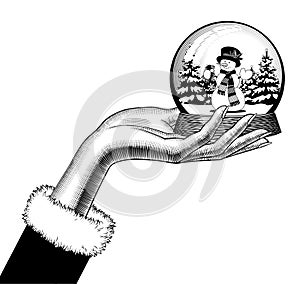 Female hand holding a snow globe with a snowman in scarf and hat