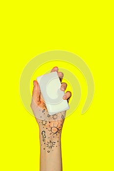 Female hand holding a soap on yellow background. Health care, `Wash hand`, coronavirus.