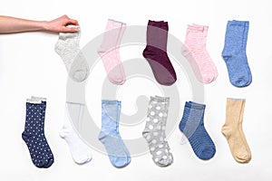 Female hand holding socks among women`s cotton socks set on white background. Fashionable socks store. Socks shopping, sale,