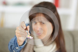 female hand holding spoon with pills