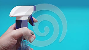 Female hand holding spray with detergent on blue background