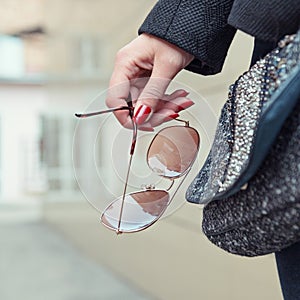 Female hand holding sunglasses.