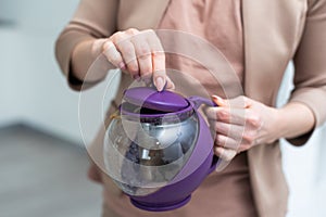 Female hand holding teapot isolated on white background.