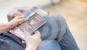 Female hand holding Thailand passport book and travel guide book at the airport, Due to the Covid-19 Epidemic pandemic concept