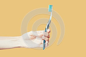 Female hand holding toothbrush with toothpaste isolated on black background. Oral care, dental hygiene concept