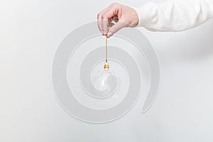 Female hand holding transparent glass Christmas ball on white backdrop. Trendy Christmas background.