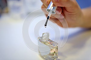 Female hand holding transparent nail Polish, blurred background, close-up. Bottle of clear nail polish with brush