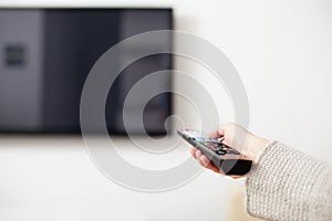 Female hand holding TV Remote Control